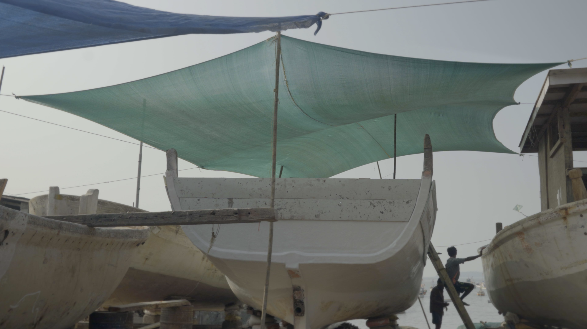 Boats under turquoise sail awnings at harbor